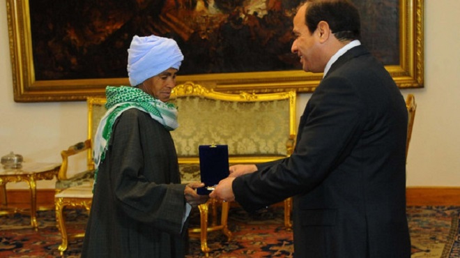 Egyptian President Abdel Fatah al-Sisi hands Sisa Abu Daooh the motherhood award. (Courtesy: Guardian newspaper)